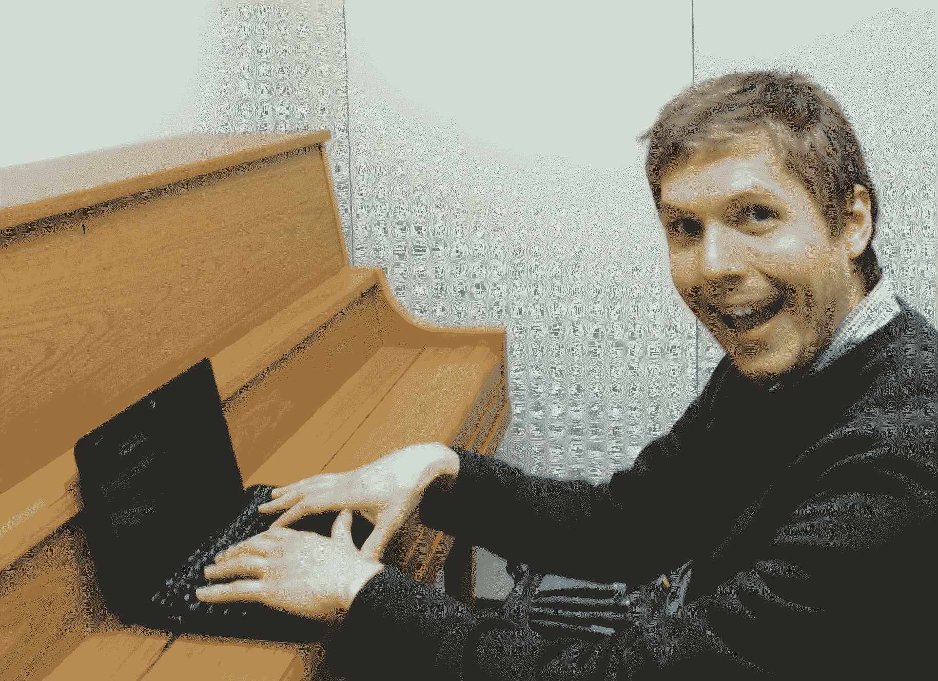 A photo of me sitting at a piano with a netbook on the keyboard making a dumb face