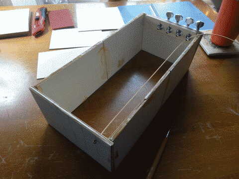 Some pieces of balsawood with tuners attached arranged into a squareish frame